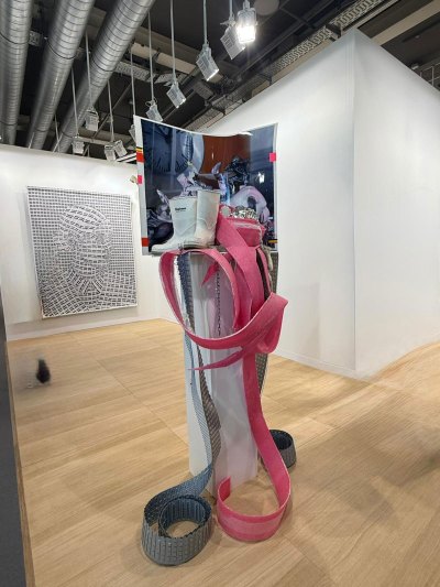 A sculpture with a white pedestal, with several things piled up on a pair of white boots.