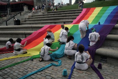 A group of people worked together to weave a long pride flag and sprinkle down the stairs.