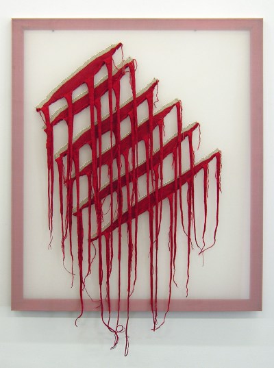 The woven piece with a white background on it with gas inside. Gas reveals the overflow of red yarn.