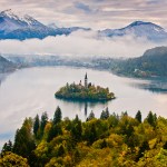 An island on a lake with mountains in the background.