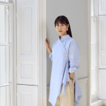 A Chinese woman stands next to a window.