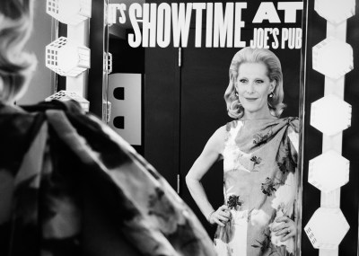 A black and white photo of a woman looking at herself in a vanity mirror.