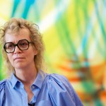 A woman in front of abstract painting.