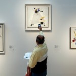 A man took a picture of a painting on the wall.