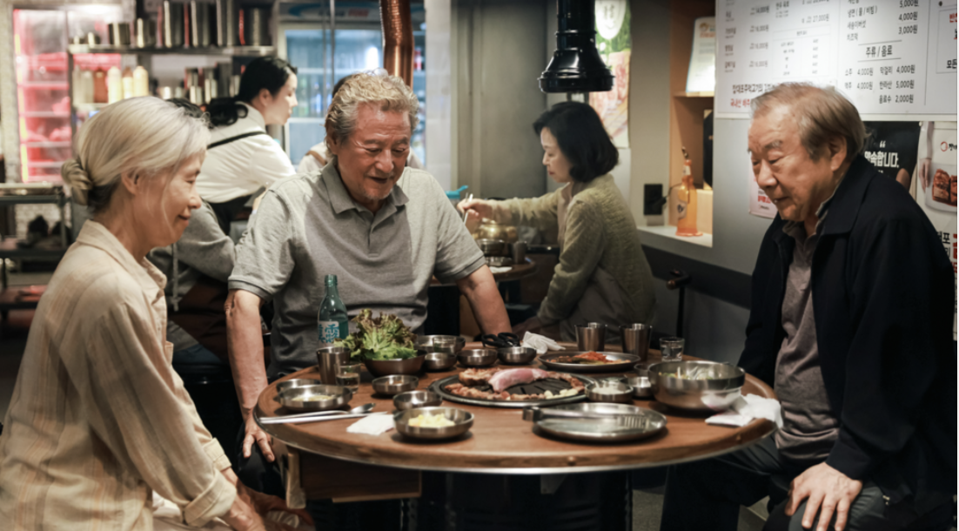 Two big Korean men and a big Korean woman are sitting at a table in the restaurant.