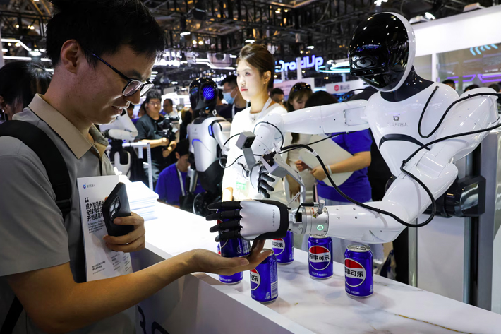 At the World Artificial Intelligence Conference in Shanghai, China, a person received a can of soda from a humanoid robot at the Agibot booth.
