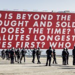 A group of soldiers under the red mural, with the words 