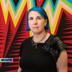 A woman with dyed blue hair stands in front of the braided with zigzag lines of various colors.