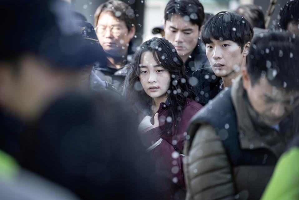 A woman is surrounded by police on a snowy day.