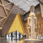 A large atrium is dominated by tall Egyptian statues and triangular entrances.