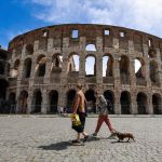 Two women walk through an ancient building.