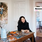A brunette woman sitting on a dining table surrounded by art.