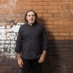 A man sticking to a graffiti wall.