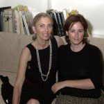 Two women were sitting on the sofa with books behind them.