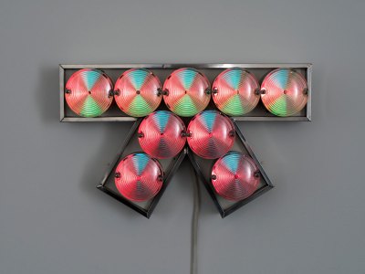 A light sculpture similar to a bow-shaped shape composed of aluminum, light bulbs and plastic laminates. 