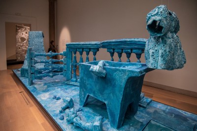 Two wooden sculptures, one of which features a toilet hanging from the ceiling.