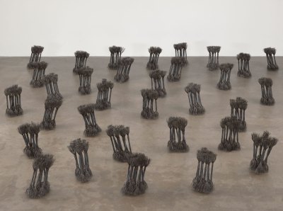A device consisting of 32 sculptures is distributed on the floor. They resemble bundles of hay and are tilted in all directions, made of wire ropes and wires. 