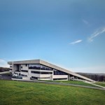 A modern museum building surrounded by grass embedded on the hillside.