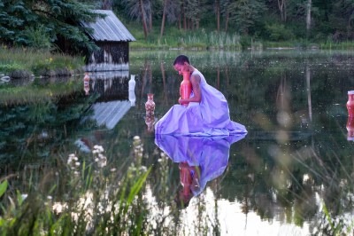 A woman appears to be walking on the lake while holding a ceramic boat.