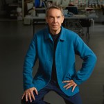 A man in blue coat looks at the camera in art studio.
