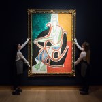 Two people holding up abstract painting.