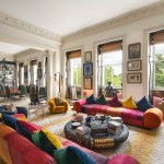 A room with large windows on the walls, sofas and lots of paintings.