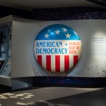 A museum display with large button reading 