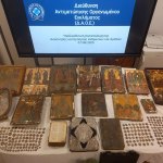 Icons, coins and other objects on the table; above is the screen in Greek.