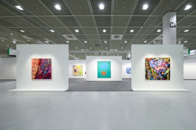 Extensive shots of an empty art fair stall with various paintings hanging on different fake walls.