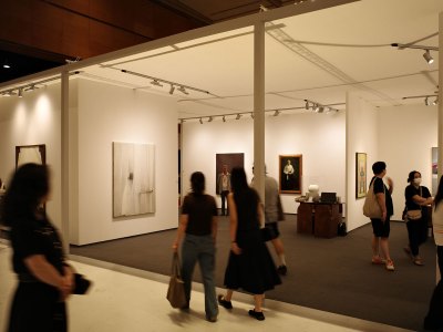 A view of an art fair, with various works on the walls and small 18th-century jars sitting on the table.