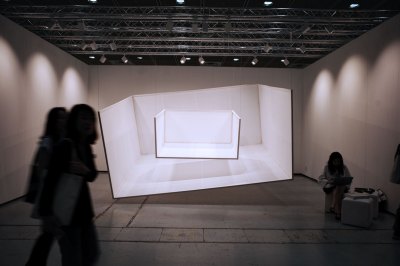 The installation shows two small versions of two empty three-sided art fair stalls hanging in an empty art fair stall.