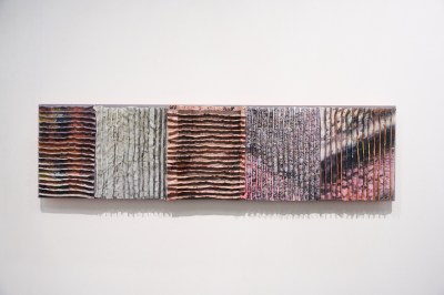 A work made of ruched together fabric that obscures the image that is printed on it.