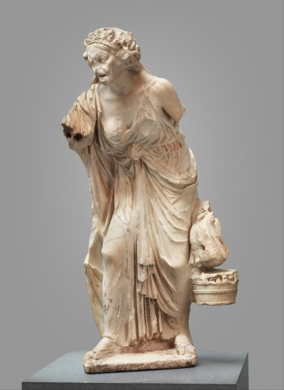 An ancient statue of an old woman walking.