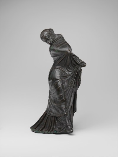 A statue of a dancer twisting beneath a fabric that covers all of her body and most of her face.