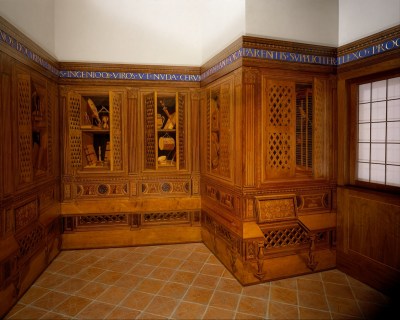 A room whose wood inlay walls resemble open cabinets containing musical instruments and knickknacks.