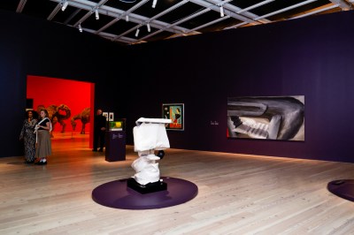 A gallery with paintings on its walls and a sculpture of an inflatable toilet in its center.