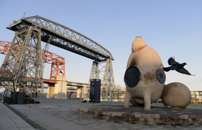 A sculpture of a bird flying over a shipyard.