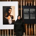 A woman standing next to a picture of a boy's limbs.