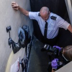 London, England - September 8: Security and attempt to block the view as forensic photographers arrive at street artist Banksy at the Royal Court of the Royal Court in London, England on September 8, 2025, in the Royal Court of London, England, believed to be considered a photograph of the new mural. Banksy released photos of his latest mural on the side of the Judicial Court of the Crown Court today, depicting a judge assaulting protesters. Within hours of his posting the image, the artwork was covered and guarded by security personnel. (Photo by Dan Kitwood/Getty Images)