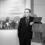 A man with arms leans against a man's sculpture.