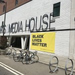 White brick wall with yellow banner reading black text that is important for black life
