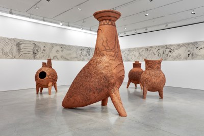 Four large-scale sculptures made of Adobe are similar to animals-human hybrids and have crayon markings on their surface.