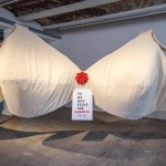 In the middle is a sculpture of a giant white bra with a label that says: ya ho nay pecho que aguante.