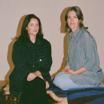 Two women sitting on the gallery floor.