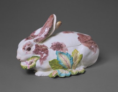 A ceramic tureen that is shaped like a rabbit with reddish-brown patches  