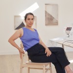 A woman sitting in a wooden chair looking at the camera.