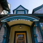 Close-up of the building with weathered wooden shoe exterior and an entrance painted turquoise and yellow entrance "Abe Museum" in front of