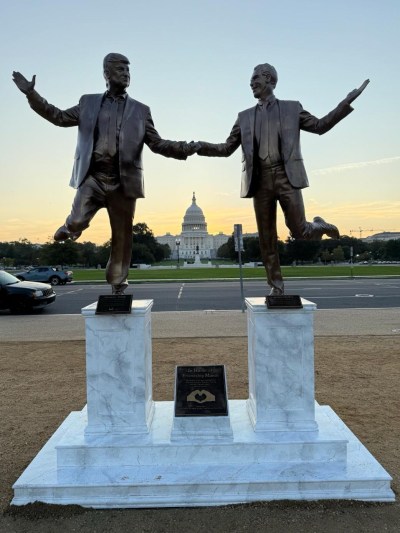 Sculpture of two men dancing on the pedestal.