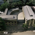 Buildings seen from a bird's-eye view surrounded by trees in a city.