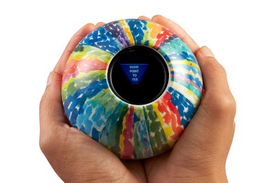 A magic eight ball with an abstract design is held in someone's hand with the message 